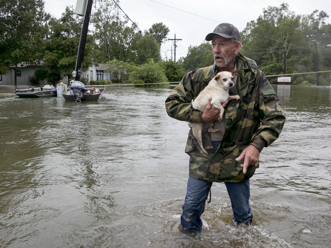 Cory (no last name given) carries his dog out of the flood on Tram Road in Beaumont, Texas, after being rescued by boat from his home after Tropical Storm Harvey on Wednesday Aug. 30, 2017. Picture: AP