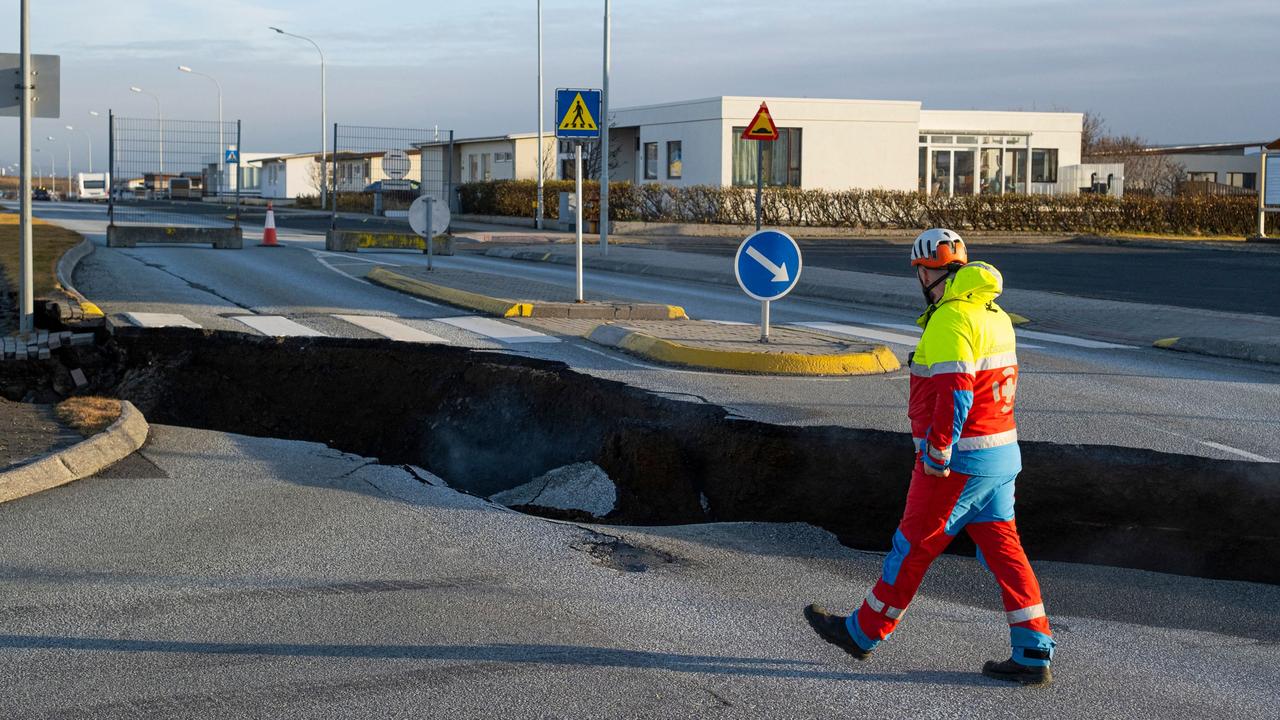 A member of the emergency services walks near a crack cutting across the main road in Grindavik on November 13. Picture: Kjartan Torbjoernsson / AFP