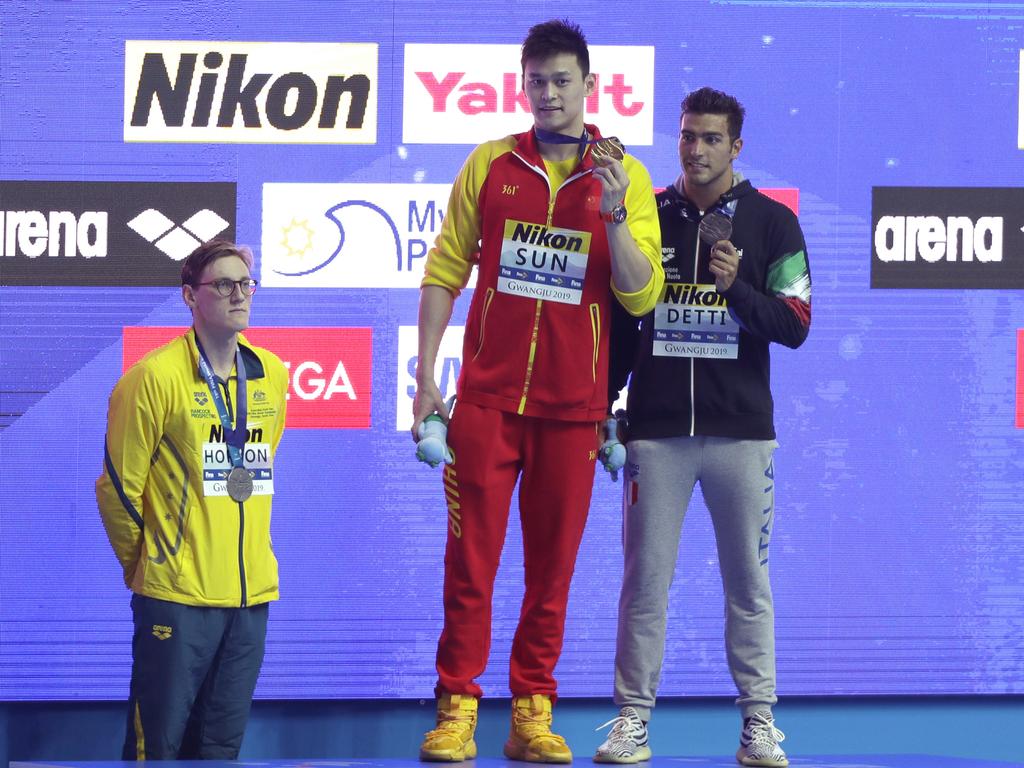 China's Sun Yang, centre, holds up his gold medal as silver medallist Australia's Mack Horton, left, stands away from the podium. Picture: Mark Schiefelbein/AP