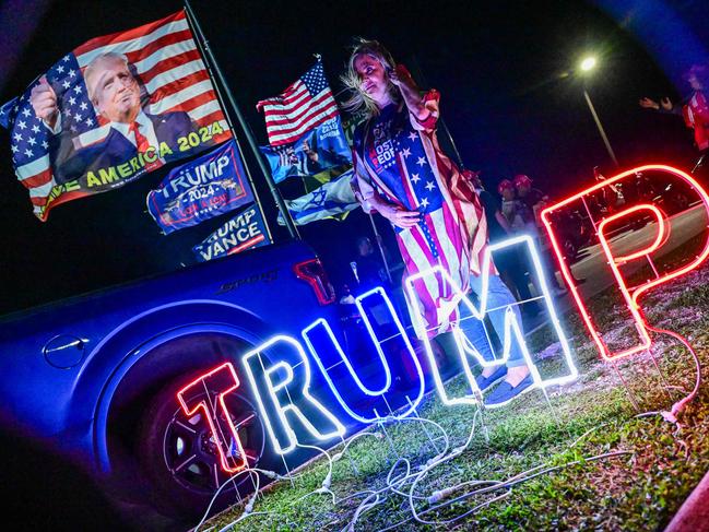 A woman wears a US flag jacket as supporters of former US president and Republican presidential candidate Donald Trump gather to show their support near his residence at Mar-a-Lago in West Palm Beach, Florida, on October 28, 2024. (Photo by Giorgio Viera / AFP)