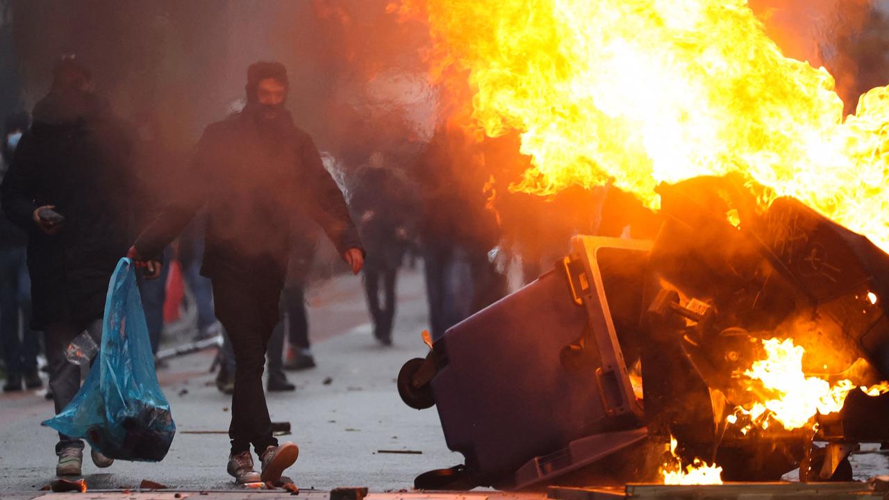 A man walks past burning rubbish as clashes erupt during a demonstration against Covid-19 measures, including Belgium’s health pass, in Brussels on November 21, 2021. Picture: AFP