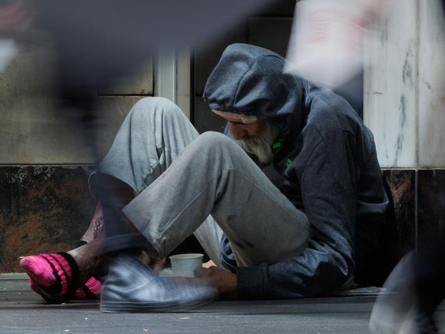 SYDNEY, AUSTRALIA - NewsWire Photos, October 29 2024. GENERIC. Inflation. Shopping. Retail. Economy. Cost of living crisis. Homelessness. Shoppers pass an elderly homeless man with severe wounds / sores on his legs outside a Woolworths in Pitt Street Mall. Picture: NewsWire / Max Mason-Hubers