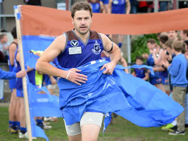 Peninsula forward Shaun Payze runs through a banner for his 300th game.