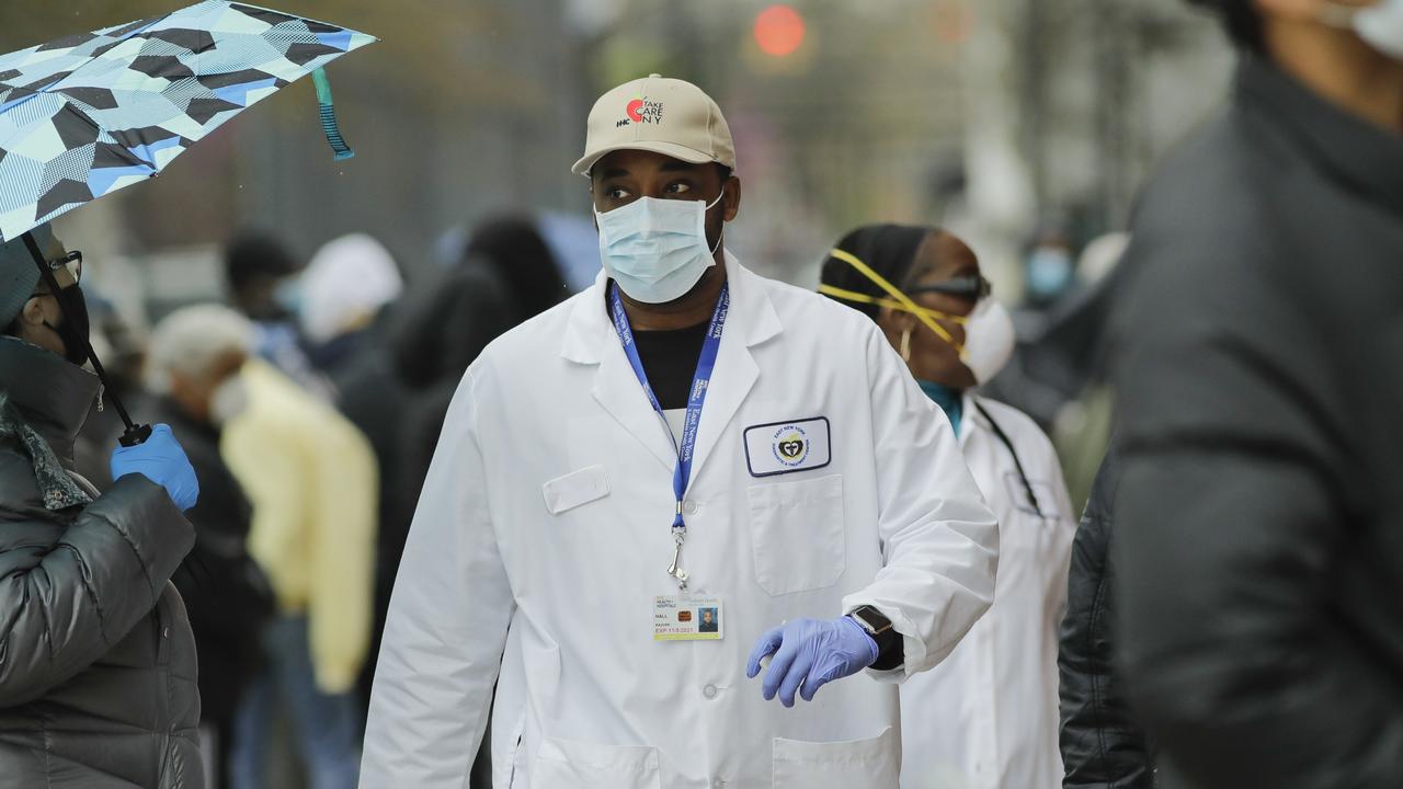 A medical worker walks past people lined up at Gotham Health East New York.