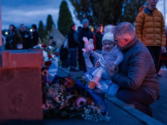 A young child with their parent lays a wreath at the base of the Cenotaph in Hobart. Picture: Tamati Smith/Getty Images