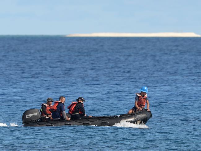 Members of a Philippine survey team sailing around Philippine-held Thitu island, with a sandbar seen in the background, in the Spratlys archipelago. Picture: AFP