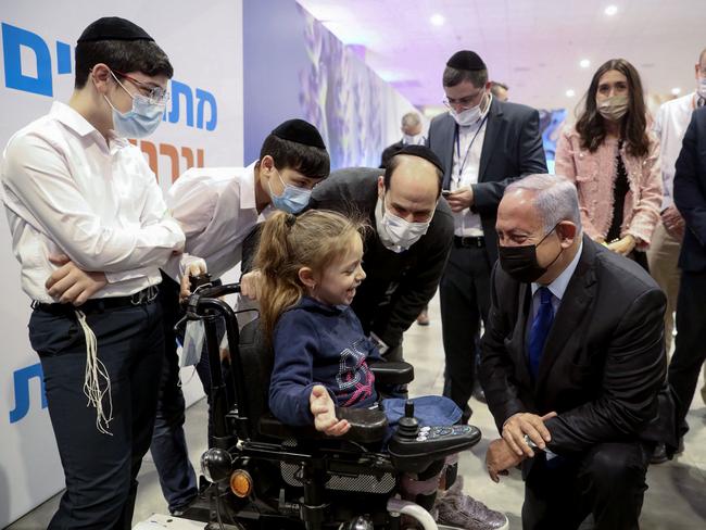 Israeli Prime Minister Benjamin Netanyahu talks to people during a visit to the COVID-19 vaccination facility in Jerusalem on January 6, 2021. - Netanyahu announced a day earlier that Israel would go into a full two-week, tight lockdown, starting January 8, including the entire education system, after health officials demanded urgent action over soaring coronavirus infection rates which have put COVID-19 wards across the country on the brink of collapse. (Photo by Marc Israel SELLEM / POOL / AFP)