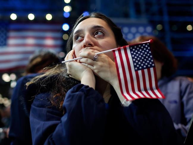 A woman holds an American flag as she watches the voting results at Democratic presidential nominee former Secretary of State Hillary Clinton’s election night event at the Jacob K. Javits Convention Center November 9, 2016 in New York City. Clinton is running against Republican nominee, Donald J. Trump to be the 45th President of the United States. Win McNamee/Getty Images/AFP == FOR NEWSPAPERS, INTERNET, TELCOS & TELEVISION USE ONLY ==