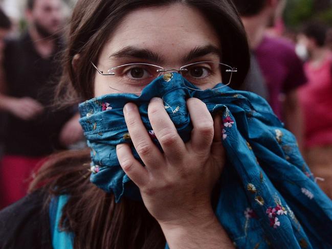 A woman raises her scarf to her face to protect herself in case of tear gas in front of European commision offices in Athens on July 2, 2015, during a demonstration supporting the no vote for the upcoming referendum. Greece's government and international creditors raised the stakes on July 2 over a weekend referendum seen as decisive for the nearly insolvent EU country's political and financial future. While Prime Minister Alexis Tsipras has urged Greeks to vote 'No' to the austerity measures demanded by international creditors, opposition parties including the centre-right New Democracy are campaigning for a 'Yes' vote in the referendum on July 5. AFP PHOTO / Louisa Gouliamaki