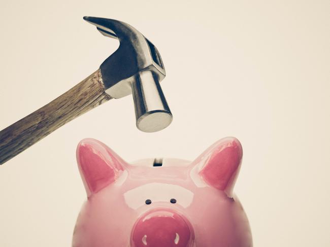 A sad pink piggy bank is about to be hit by a hammer isolated