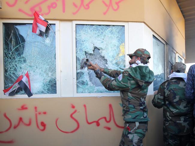 Members the Hashed al-Shaabi, a mostly Shiite network of local armed groups trained and armed by powerful neighbour Iran, smash the bullet-proof glass of the US embassy's windows in Baghdad. Picture: AFP