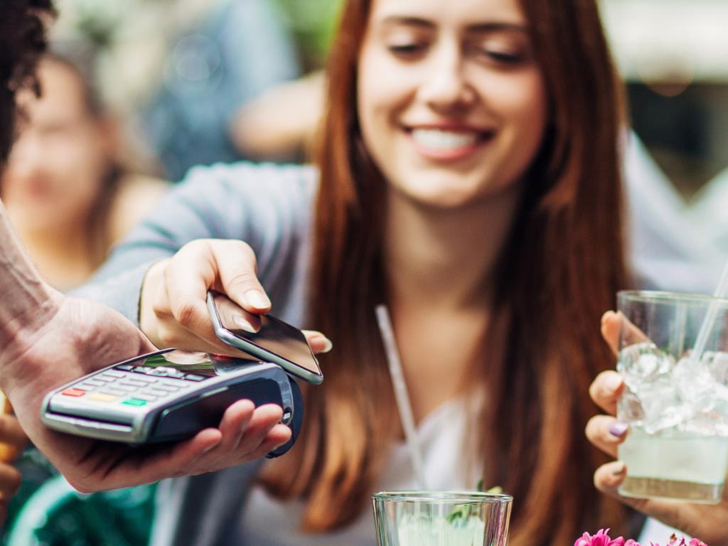 Young people in a cafe making a contactless payment through a mobile phone