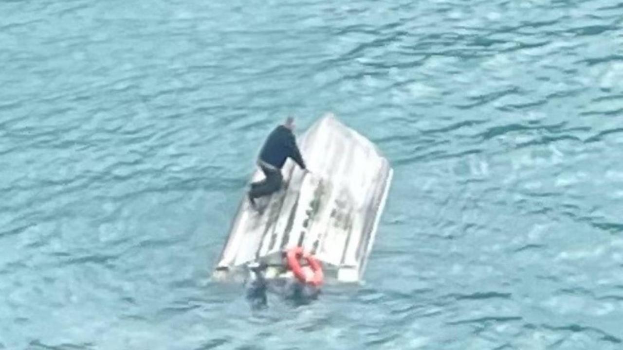 Photo from a helicopter circling the upturned vessel in Goose Bay with one person seen on the hull. Photo / Supplied /NZ Herald.