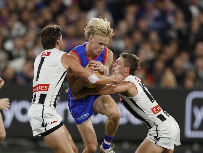 NCA. MELBOURNE, AUSTRALIA. 21th March, 2025 .  AFL Round 2. Footscray vs Collingwood at the MCG.  Bulldog Sam Davidson tries to barge through the tackle of Patrick Lapinski and Harry Perryman of the Magpies   . Picture: Michael Klein