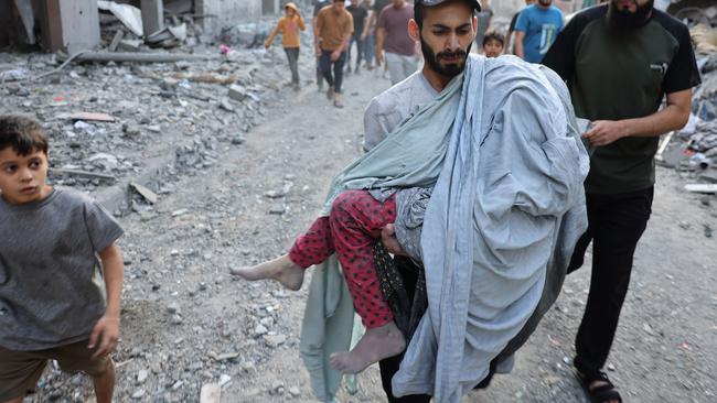 A Palestinian man carries the covered body of a girl removed from the rubble of a building following the Israeli bombardment of the Nuseirat refugee camp, in the central Gaza Strip on October 30, 2023. Picture: Mohammed Abed / AFP