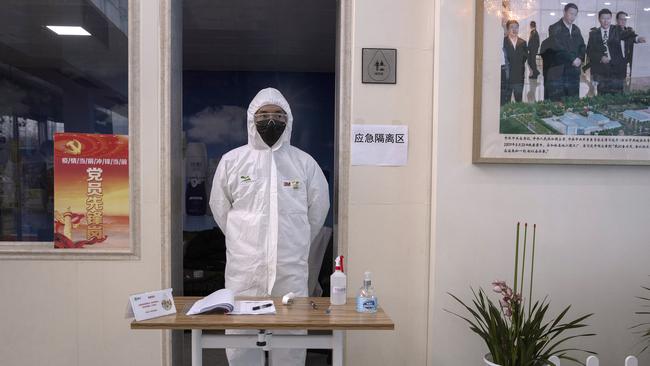 A worker stands near a picture showing Chinese President Xi Jinping visiting the Mengniu dairy factory in Beijing.