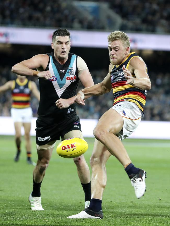 Crows Hugh Greenwood gets his kick away as Power’s Tom Rockliff close in at Adelaide Oval.  Picture Sarah Reed