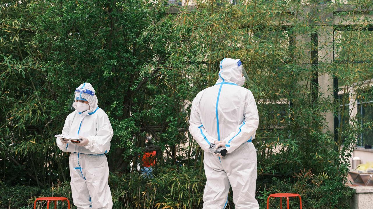 Community volunteers wearing personal protective equipment stand during a test for Covid-19 during lockdown in Shanghai on April 19, 2022. Picture: Liu Jin / AFP