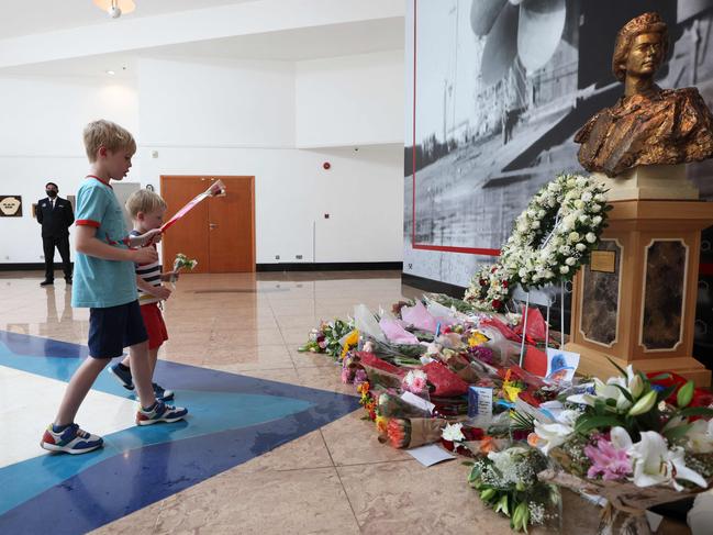 People lay flowers under the bust of Queen Elizabeth II during a memorial for the Queen at the British Consulate in Dubai. Picture: AFP.