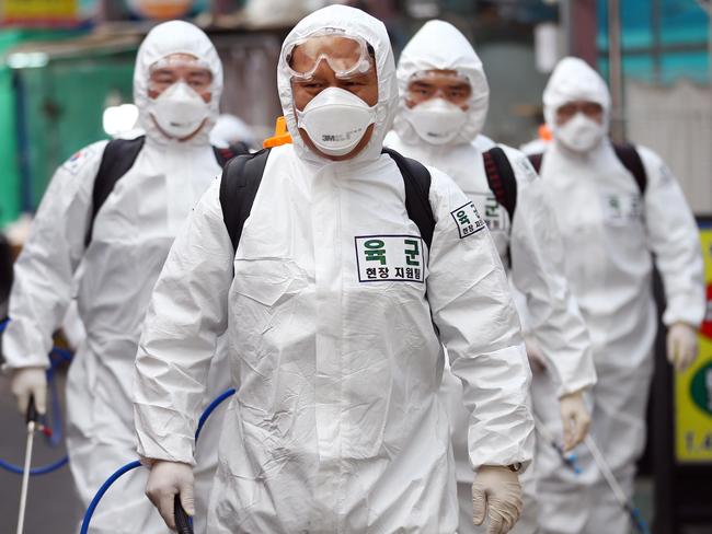 South Korean soldiers wearing protective gear spray disinfectant as part of preventive measures against the spread of the COVID-19 coronavirus at a market in Daegu. Picture: AFP