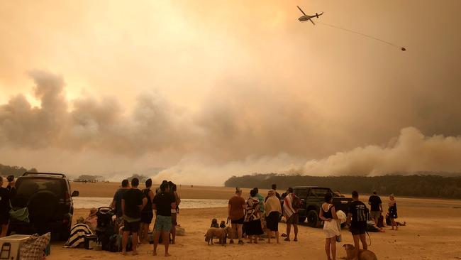 A waterbombing helicopter approaches the Currowan fire front near Lake Conjola on New Year's Eve.