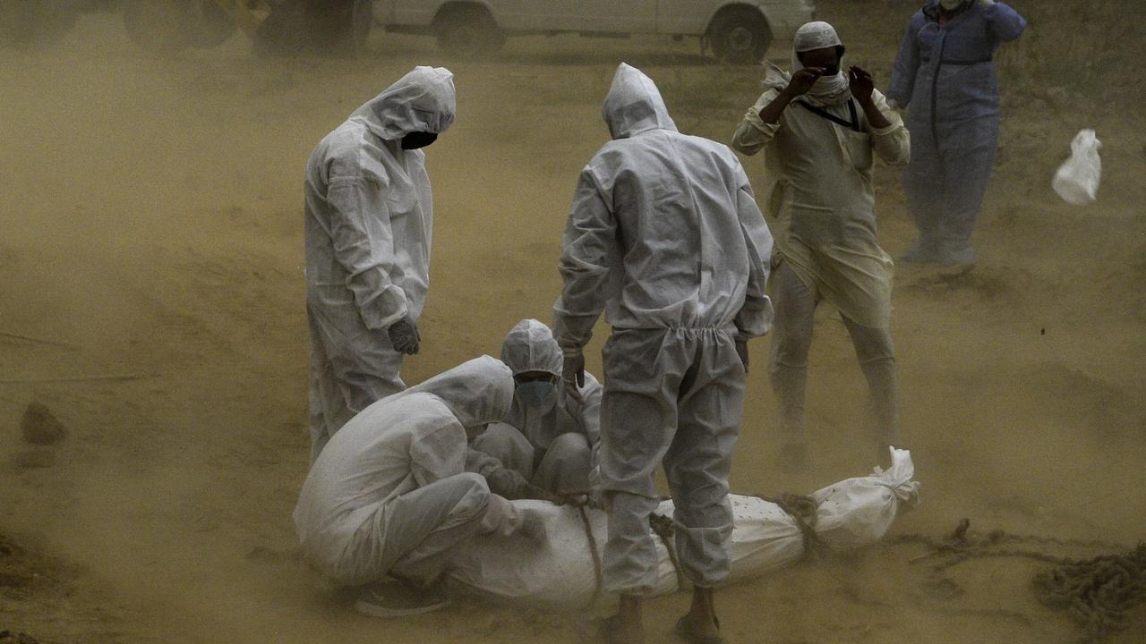 Relatives wearing protective gear tie up the body of a victim who died from COVID-19 before the burial at a graveyard in New Delhi on May 10, 2020. Picture: AFP