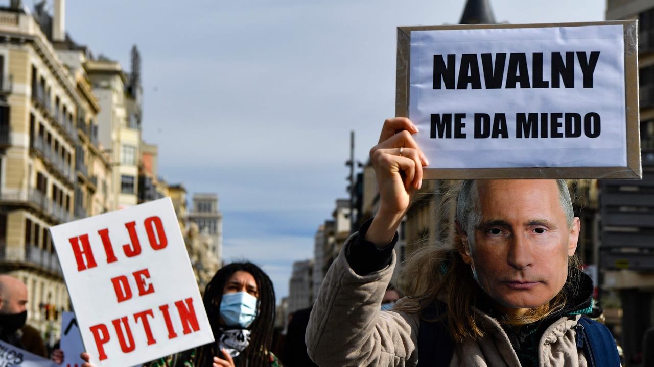 A woman holds a placard reading ‘Son of Putin’ as another wears a mask of Vladimir Putin with a placard which says ‘Navalny scares me’ during a protest. Picture: Pau Barrena/AFP