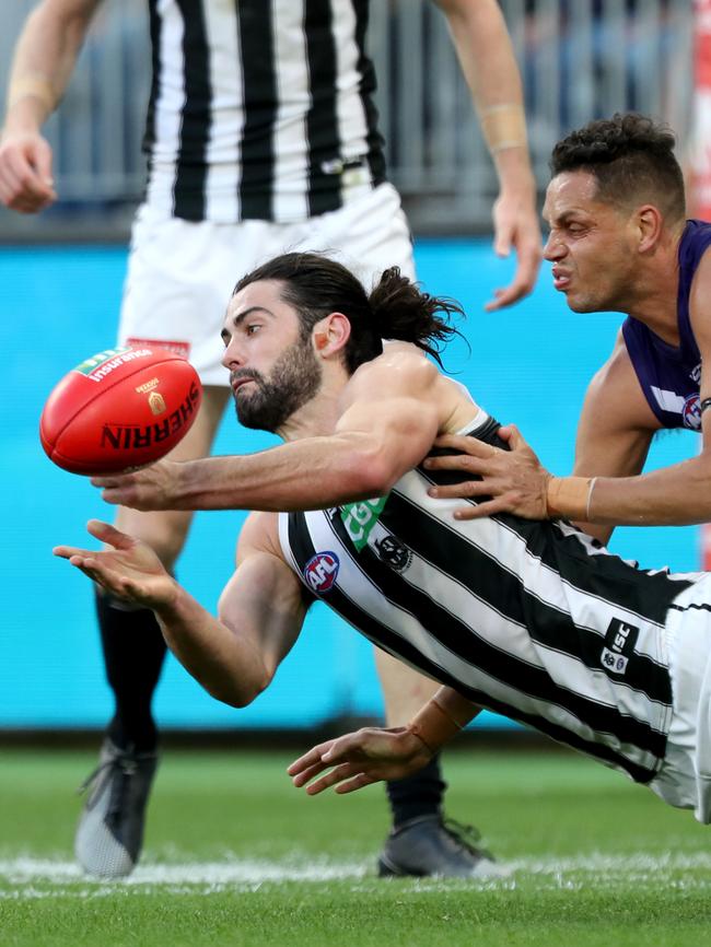 Brodie Grundy handpasses under pressure from Michael Johnson. Picture: AAP Image/Richard Wainwright