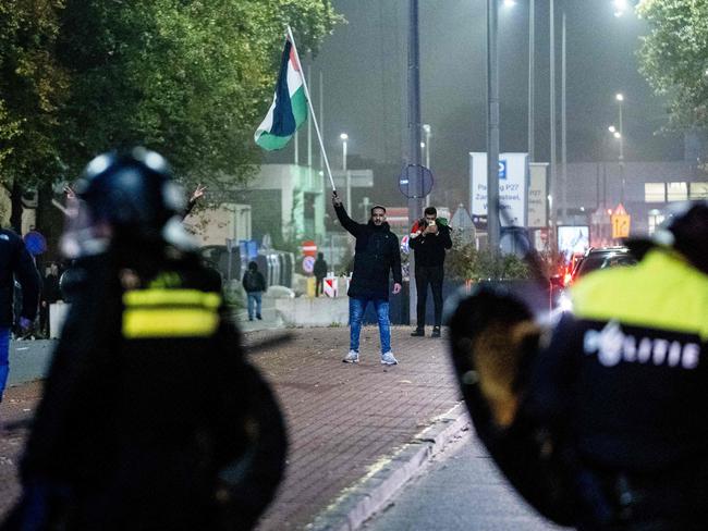 A supporter waves a Palestinian flag in front of Police officers from Mobile Unit (ME) during a pro-Palestinian demonstration.