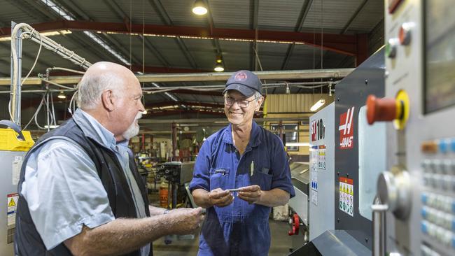 Bruce Alvey talks to Kim Jong, next to their Haas CNC lathe machine, which produces some of the special parts that make an Alvey reel.