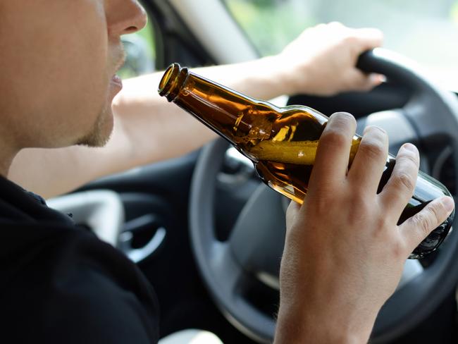 The concept of alcohol driving crime - closeup of young male driver hands with steering wheel and bottle of beer. Drink driving generic. Picture: iSTOCK