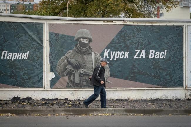 A man walks past a wall adorned with banners honouring Russian servicemen participating in Russia's military action in Ukraine