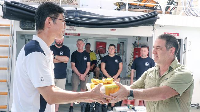 Marine Archaeologist David Steinberg presents Takenobu Hamaguchi with sand from the vicinity of the Japanese WWII wreck of I-124 submarine as a dive expedition returns from a Heritage documentation trip. Picture: Glenn Campbell