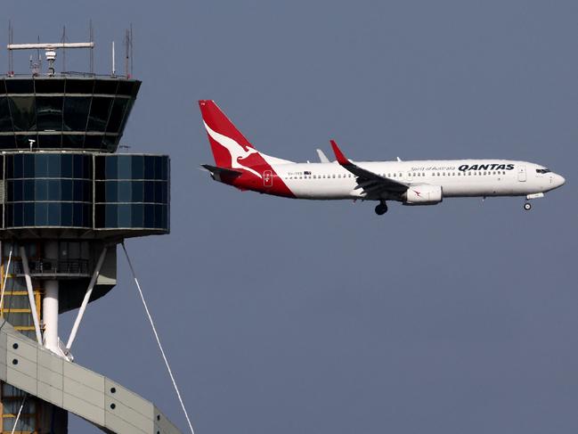 This picture taken on December 6, 2023 shows a Qantas Airways Boeing 737-800 passenger aircraft on final approach for landing in front of the control tower at Sydneyâs Kingsford Smith international airport. (Photo by DAVID GRAY / AFP)