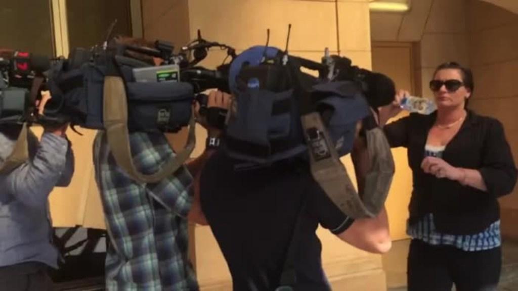 Woman sprays media with water bottle outside court