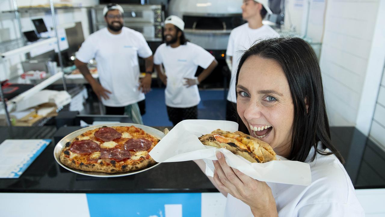 Roma Driscoll with holds a fold-up pizza at the newly opened Francesca's at Glenelg, with co-owners Aman Takher, Nilavan Baskaran and Aiden O'Sullivan. Picture: Mark Brake