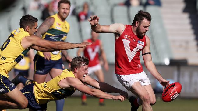 North Adelaide Max Thring gets his kick away from Jared Petrenko and Nicholas Hayes before going down with a calf injury. Picture Sarah Reed