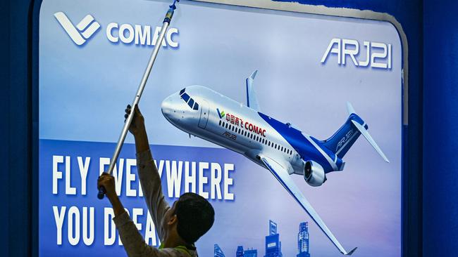 A worker prepares China's Comac booth ahead of the Singapore Airshow in Singapore on February 18, 2024. (Photo by Roslan RAHMAN / AFP)