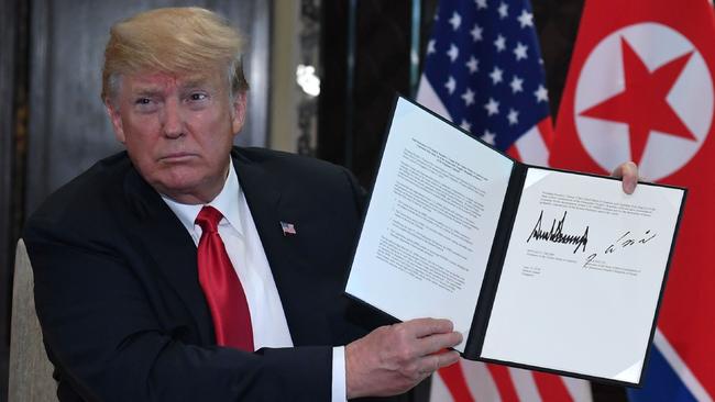 President Trump holds up a document signed by himself and Kim Jong-un. Picture: AFP