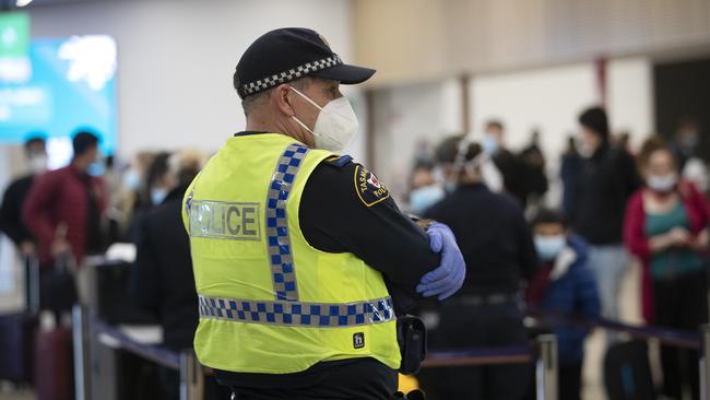 A Tasmania Police officer keeps watch on passengers arriving at Hobart airport from Melbourne. Picture: CHRIS KIDD