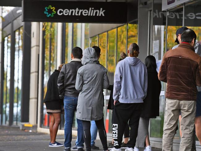 People queue up outside a Centrelink office in Melbourne on April 20, 2020, which delivers a range of government payments and services for retirees, the unemployed, families, carers and parents amongst others. - A report from the Grattan Institute predicts between 14 and 26 per cent of Australian workers could be out of work as a direct result of the coronavirus shutdown, and the crisis will have an enduring impact on jobs and the economy for years to come. (Photo by William WEST / AFP)