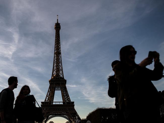 (FILES) This file photo taken on October 31, 2016 shows tourists taking selfies in front of the Eiffel tower in Paris on October 31, 2016.  The strike at the Eiffel Tower continued on December 13, 2016 evening as the pursuit of the movement will be discussed on December 14 morning, a representative of the inter-union told to AFP . / AFP PHOTO / PHILIPPE LOPEZ