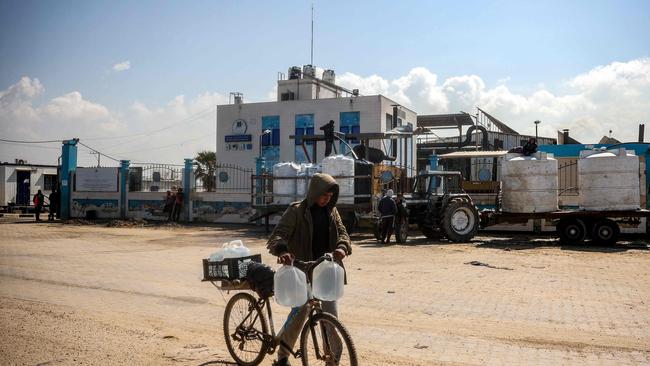 A youth pushes a bicycle loaded with filled-up water containers outside the Southern Gaza Desalination plant. Picture: AFP