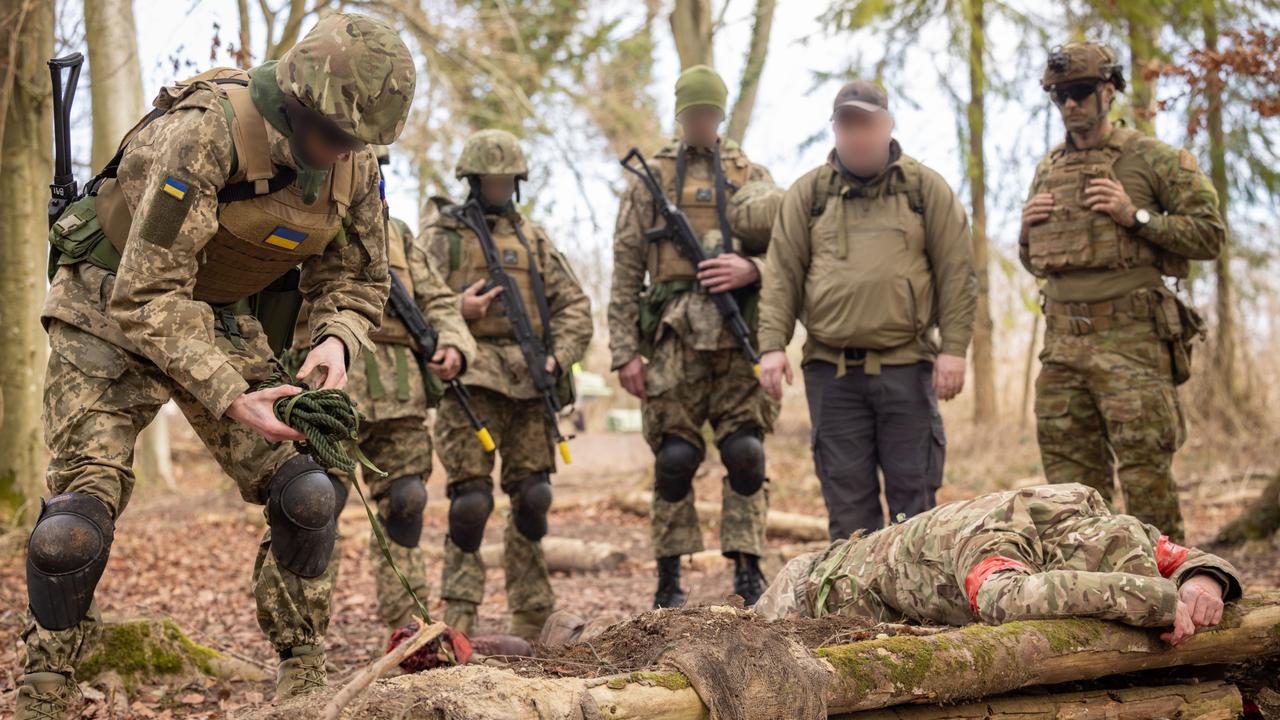 An Australian Army soldier instructs a Ukrainian recruit on how to search a casualty with a suspected booby trap during the first rotation of Operation Kudu in the United Kingdom. A simulated booby trap for training purposes was used.