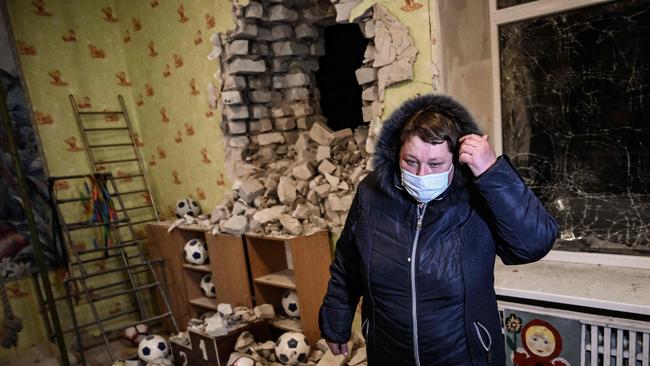 A woman stands inside among debris after the reported shelling of a kindergarten in the settlement of Stanytsia Luhanska, Ukraine, on February 17, 2022. (Photo by Aris Messinis / AFP)