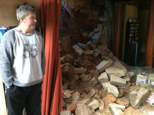 Mark Campbell stands inside his rented Mitcham house, where floodwaters sent rocks and mud through a feature window.