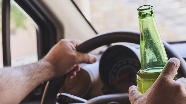 An unrecognizable man drinking beer while driving car. Concepts of driving under the influence, drunk driving or impaired driving. Drink driving generic. Picture: iSTOCK