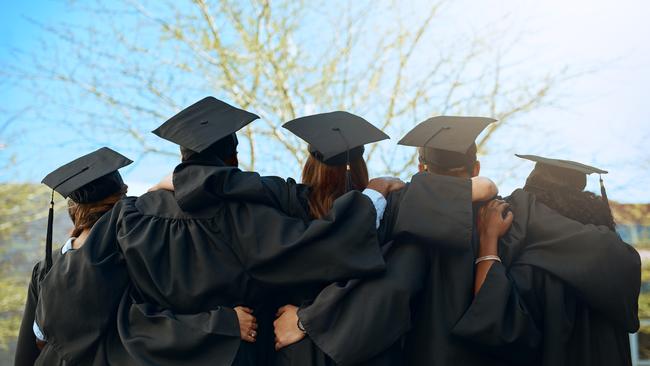 Rearview shot of a group of young students embracing on graduation day