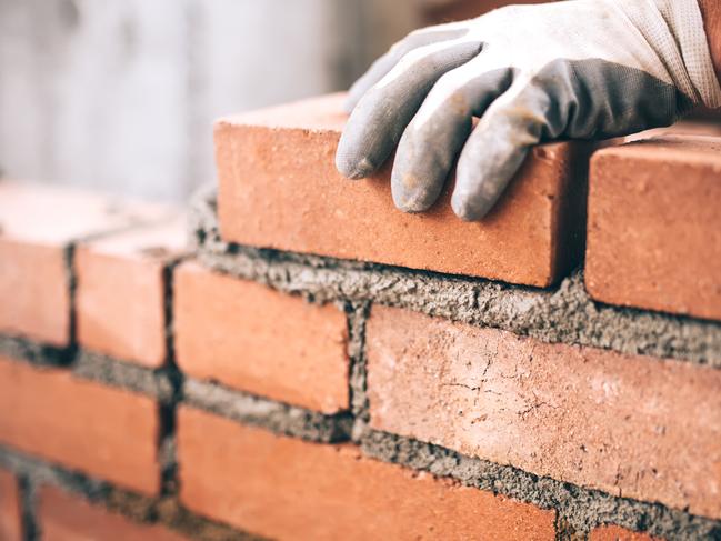 Close up of industrial bricklayer installing bricks on construction site. tradesman generic