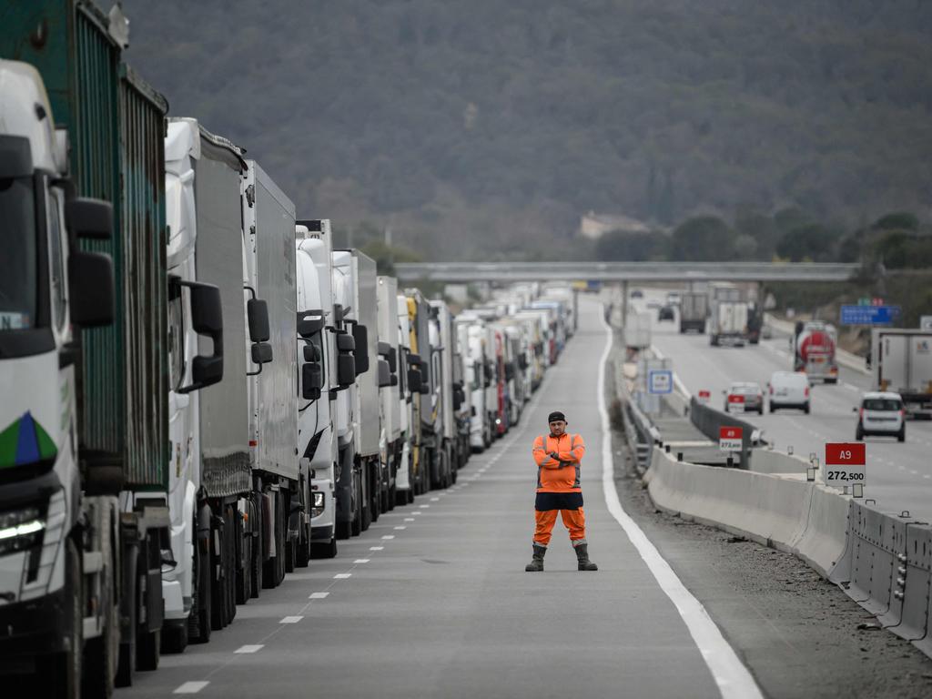 A driver looks towards protesters as they check the contents inside trucks at the A9 highway exit linking Spain and France to block the tractors and farmers as part of nationwide protests.